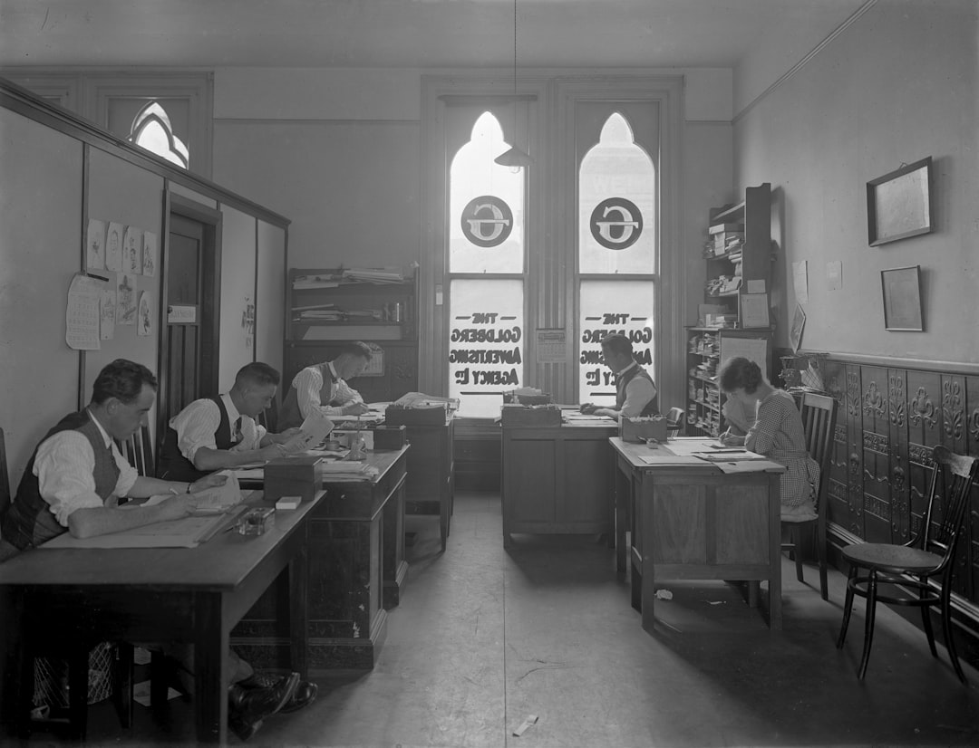 Men working in a vintage office with arched windows.