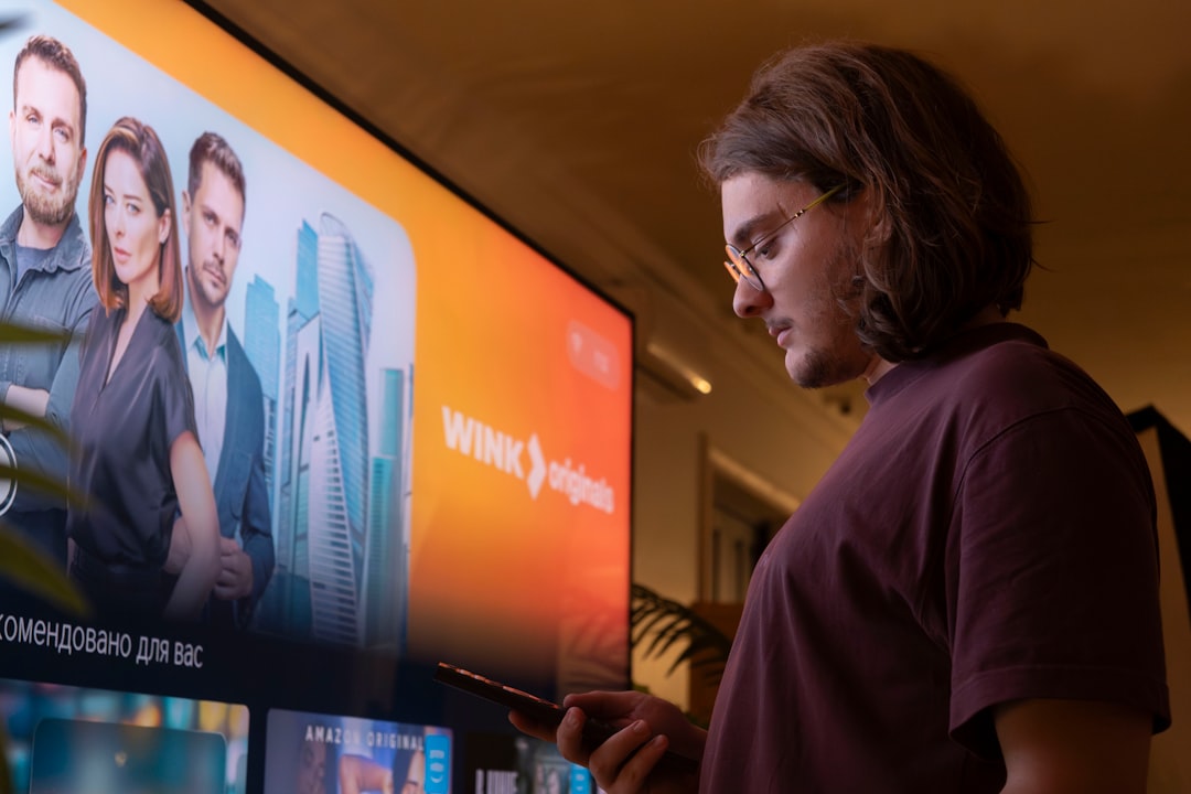 Man watching TV holding a smartphone