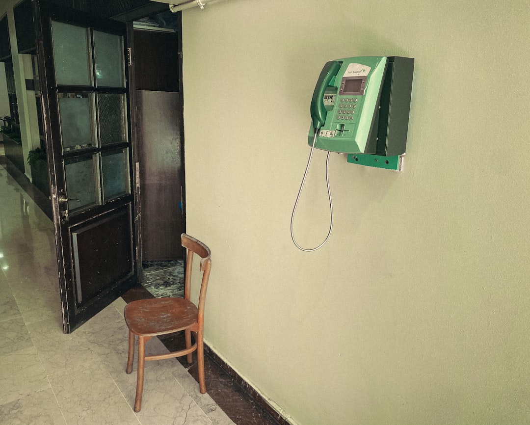 a chair next to a phone on a wall